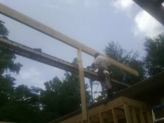 Carpenter setting a ridge beam over a new addition frame — Ice Dam Removal by Roofing Brothers in Mc Gaheysville