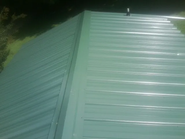 New green metal panels meeting at the ridge of a roof — Flat Roof Repair work by our crew in Mc Gaheysville