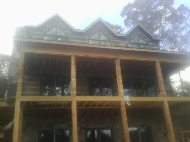 Dormers and porch framing on a large log home under construction — Roof Coating work by our crew in Mc Gaheysville