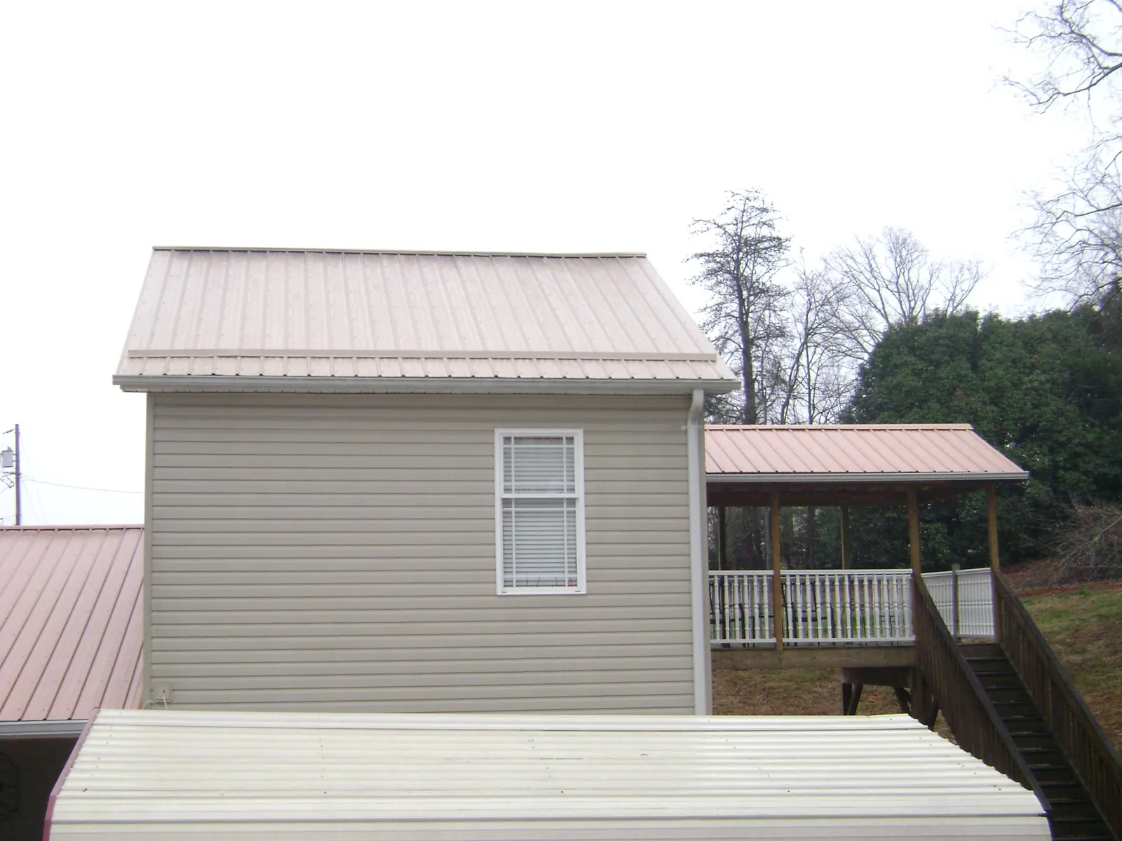 Tan metal roofs on a two story addition and attached porch, from a Roof Replacement job in Mc Gaheysville