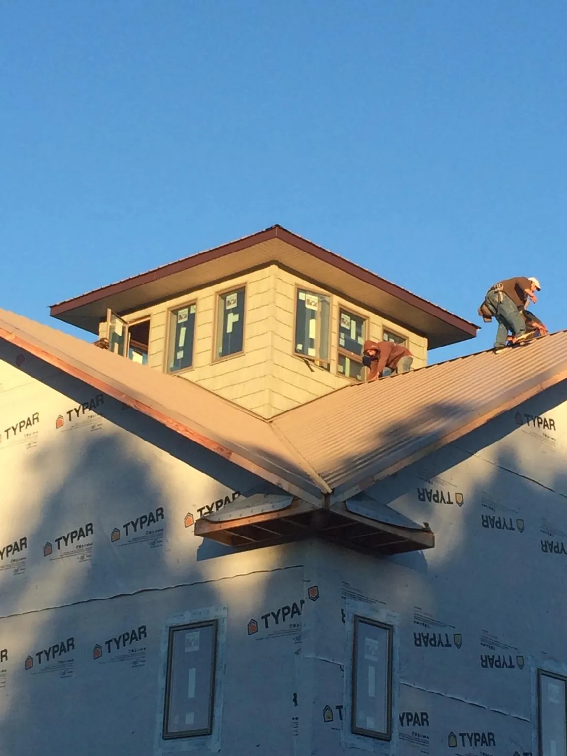 Roofers working around a rooftop cupola on a new metal roof at sunset — Roof Waterproofing in Mc Gaheysville by Roofing Brothers